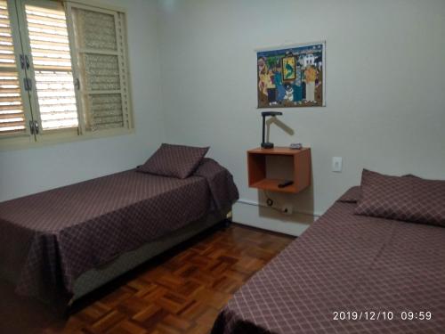 皮拉西卡巴CASA 230 - Guest House的一间卧室配有两张床和一张带台灯的桌子