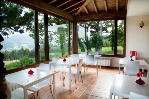 普拉维亚La Casa de la Abuela Milagros的用餐室配有白色的桌椅和大窗户