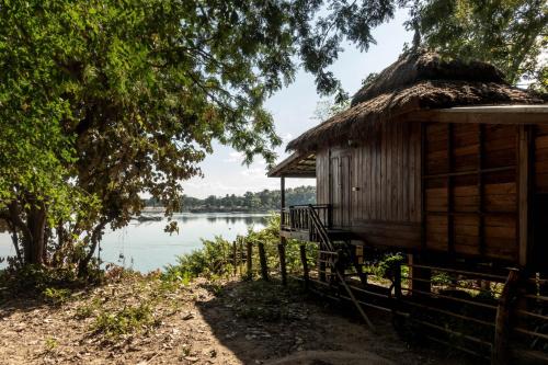 Ban KhonPomelo Restaurant and Guesthouse's Fishermen Bungalow & A Tammarine Bungalow River Front的湖畔茅草屋顶的房子