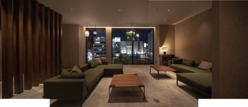 长崎hotel H2 TRIP&BUSINESS NAGASAKI的带沙发、桌子和窗户的客厅