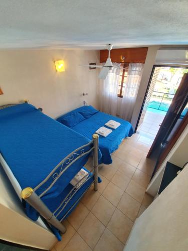 维拉卡洛斯帕兹Hotel Carlos Paz的一间卧室配有一张带蓝色床单的床和一扇窗户。