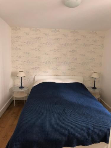 多维尔Charmante maison cœur de ville La Gare des vacances的一间卧室配有一张蓝色的床和两盏灯。