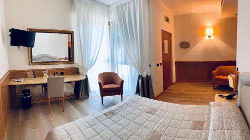 罗纳特波佐罗Airport Hotel Malpensa的一间卧室配有一张床、一张书桌和一面镜子