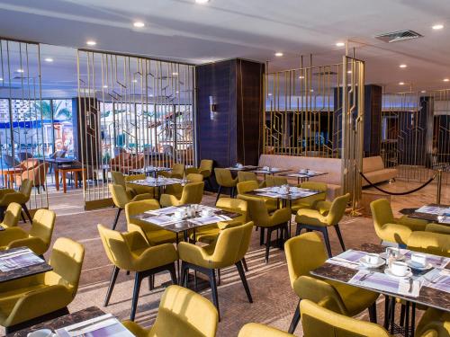 提比里亚凯撒提贝利亚斯高级酒店的餐厅设有桌子和黄色的椅子以及窗户。