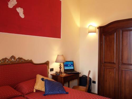 蒙特卡蒂尼泰尔梅小城堡酒店的一间卧室配有一张床和一张带笔记本电脑的书桌
