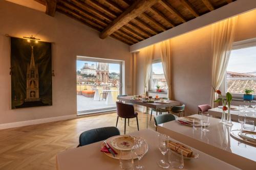 罗马Poēsis Experience Hotel的一间带桌椅的用餐室和大窗户