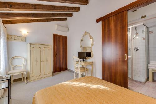 威尼斯Hotel Bernardi Semenzato的一间带一张床和一张书桌的卧室以及一间浴室。