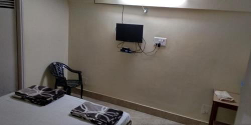 贾姆谢德布尔Adarsh lodge的一间设有床铺和墙上电视的房间