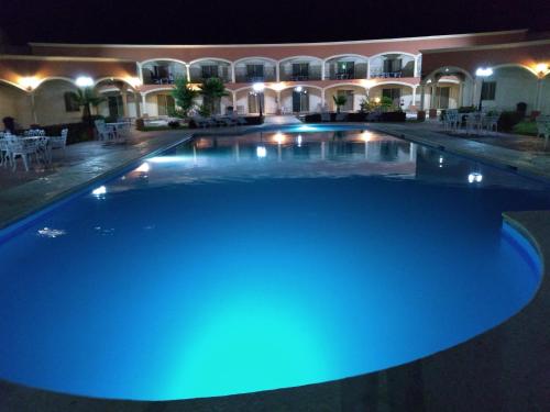 Ciudad JiménezHotel Jiménez Plaza的夜间大型游泳池,灯光蓝色