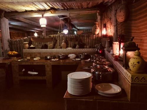Al WāşilNomadic Desert Camp的厨房配有带盘子的桌子
