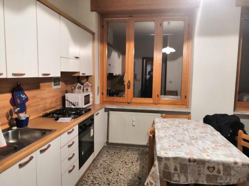 Miroglioda Alessandra e Fabio的厨房配有白色橱柜、水槽和桌子