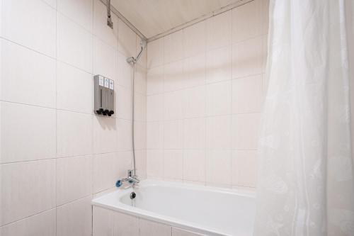 新竹水蜜桃时尚旅店的白色的浴室设有浴缸和淋浴帘