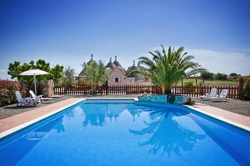 马丁纳弗兰卡特鲁利伊尔卡斯塔尼诺酒店的蓝色游泳池,带两把椅子和房子