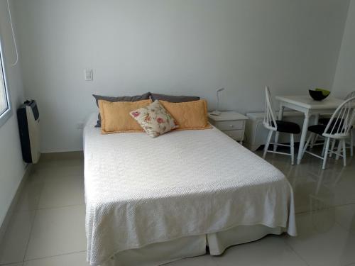 布兰卡港La Suitte的卧室配有带枕头和桌子的白色床