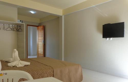 特拉曼达伊Lebanon Praia Hotel的卧室配有一张床和壁挂式平面电视。