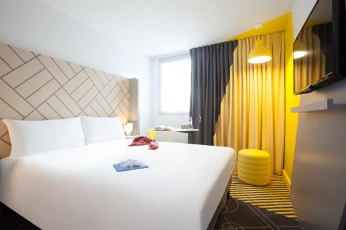巴黎巴黎马塞纳奥林匹兹宜必思尚品酒店的酒店客房设有白色的床和黄色的墙壁