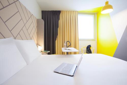 巴黎巴黎马塞纳奥林匹兹宜必思尚品酒店的坐在酒店房间床上的笔记本电脑