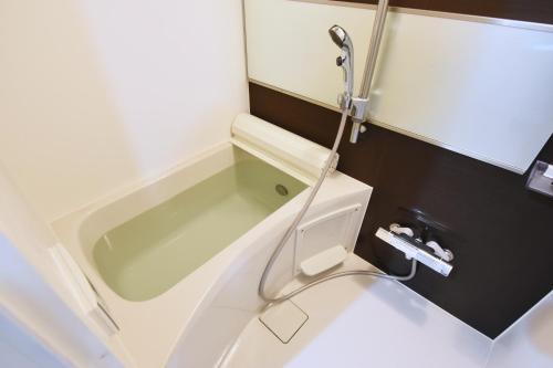 东京Tune Inn Ebisu的带浴缸和卫生间的浴室。