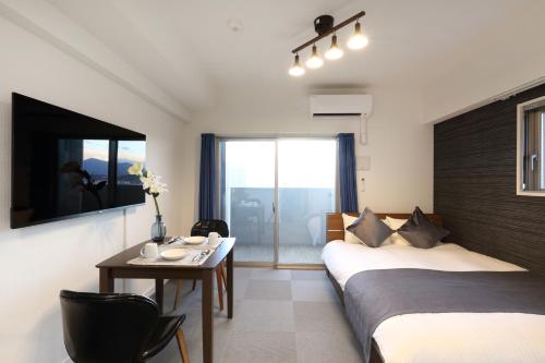 福冈The Grand Residence Hotel Hakata的酒店客房带两张床、一张桌子和一张桌子。