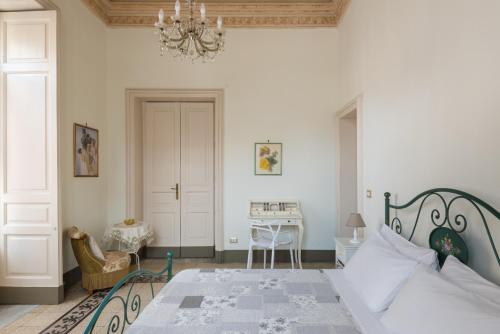 卡塔尼亚Palazzo Arcidiacono - luxury holidays的一间卧室配有一张带吊灯的床和一张书桌。