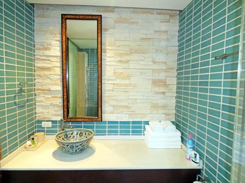 象岛海滩公寓的浴室设有水槽、镜子和蓝色瓷砖