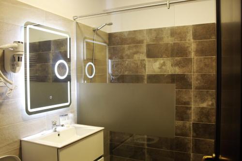 福克沙尼Pensiunea Romeo Resort的浴室配有盥洗盆和带镜子的淋浴