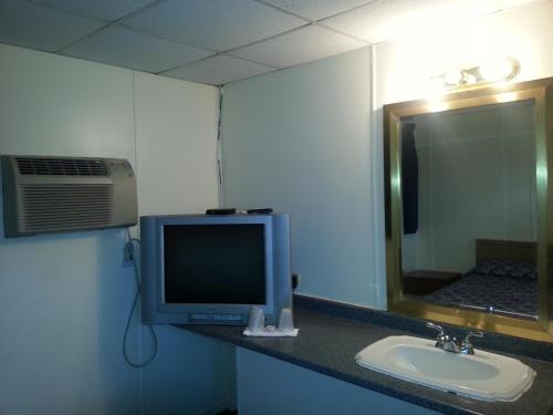 阿弗内尔美洲汽车旅馆的一间带电视、水槽和镜子的浴室