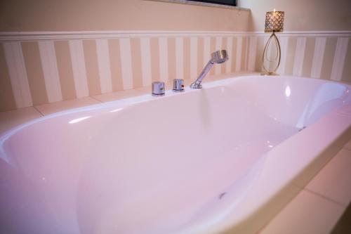 RóżanHotel Avangarda的浴室内设有带水龙头的大型白色浴缸