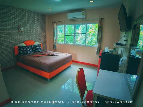 杭东清迈自行车度假村的一间卧室配有橙色的床和窗户。