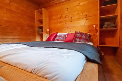 施利尔塞Ruhige Chalets mit Seeblick in zentraler Lage的木制房间中的一张床位,配有红色枕头