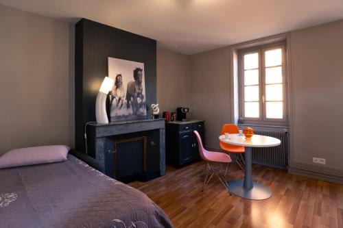 克卢尼Les Orchidées的一间卧室配有一张床、一张桌子和一个壁炉