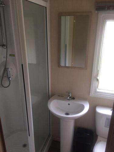 尚克林Isle of Wight Caravan的一间带水槽、淋浴和镜子的浴室