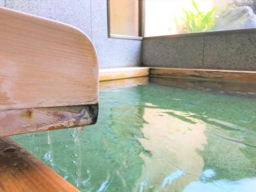 箱根K's House Hostels - Hakone Yumoto Onsen的木板凳上水源源源源的游泳池