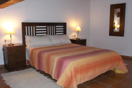 Las Cuevas de CañartCasa Rural El Temple的一间卧室配有一张带2个床头柜的大床