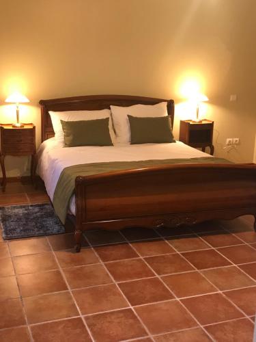 RumegiesGite Le Rucher的一间卧室配有一张带两盏灯的大木床。