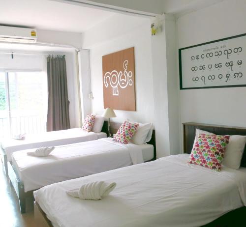 Ban Khun Yuam永特酒店的客房设有三张床,配有白色床单和枕头。