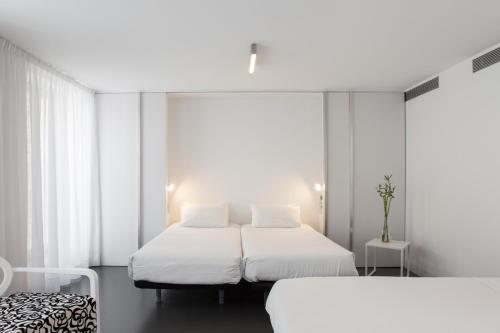 圣地亚哥－德孔波斯特拉摩尔酒店的配有2张床的白色墙壁和窗户客房