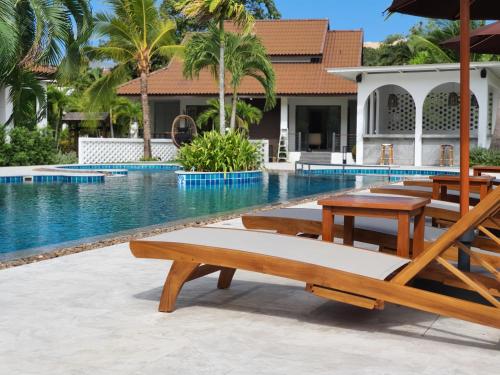 卡塔海滩BLU PINE Villa & Pool Access - SHA Plus的房屋旁的带木桌和椅子的游泳池