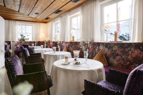 圣克里斯托弗阿尔贝格圣克里斯托夫阿尔卑斯酒店的餐厅设有白色的桌椅和窗户。