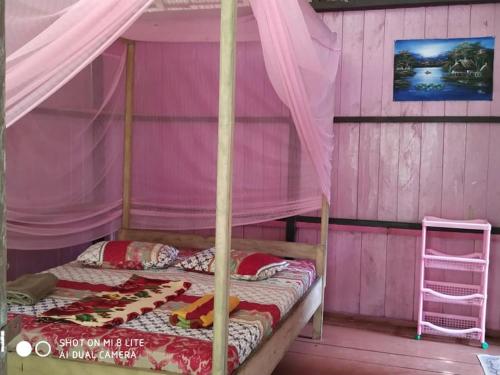 BatudakaSunset Beach的粉红色客房内的卧室配有一张天蓬床
