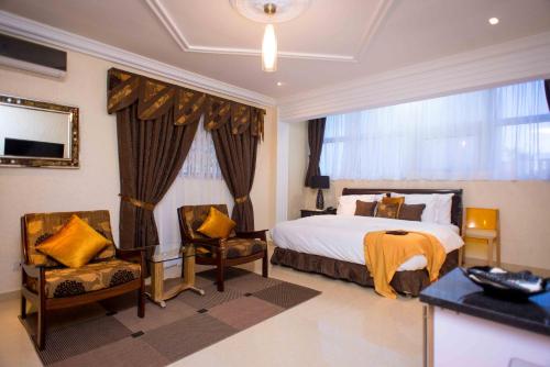 阿克拉The Ritzz Exclusive Guest House的酒店客房,配有一张床和两把椅子