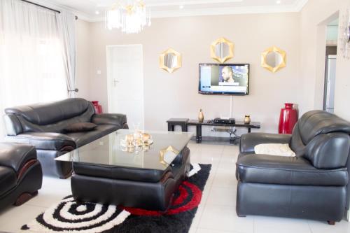 哈拉雷Villa Prince的客厅配有皮革家具和桌子
