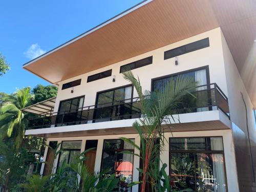 曼努埃尔安东尼奥Hotel Manuel Antonio Park的白色的房子,有黑窗和棕榈树