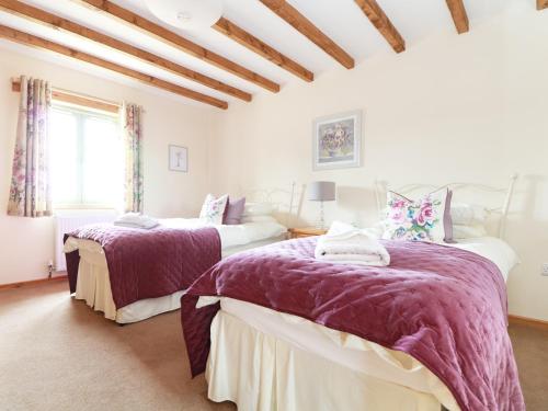 特鲁罗Hawthorn Cottage的一间卧室配有两张紫色毯子的床