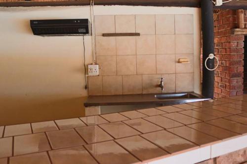 贝拉贝拉Die Huis - Self Catering的厨房设有瓷砖台面和水槽
