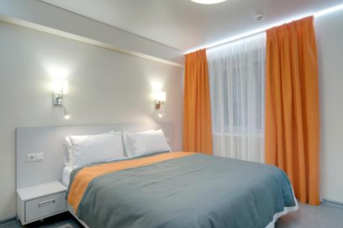 基辅Arena Summit Apart Hotel的一间卧室配有床和橙色窗帘的窗户