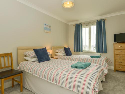 滨海比格伯里3 Tarifa的一间卧室设有两张床、一台电视和一把椅子