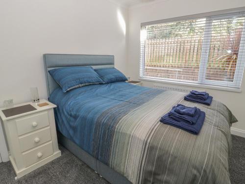 科尔温湾The Nook的一间卧室配有一张床、床头柜和窗户