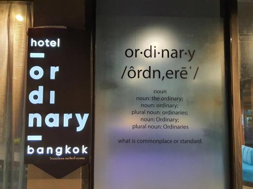 曼谷Hotel Ordinary Bangkok的玻璃门上有两个标志,上面写着旅馆或临时的笑话