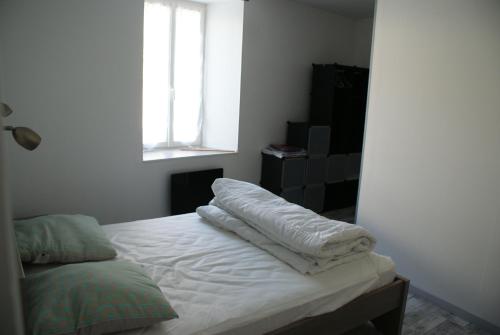 马雷讷Paranthese à Marennes的一间卧室配有一张带白色床单的床和一扇窗户。